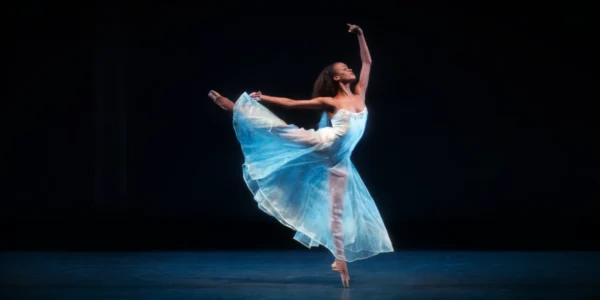 6 Dancers at New York City Ballet Promoted featuring India Bradley wearing a long, light blue romantic tutu while in arabesque on pointe.