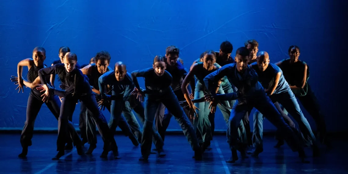 Joburg Ballet Communion of Light Review 2025 featuring a group of dancers in pants and shirts in shades of blue, hunched over looking directly at the audience.